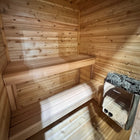 Inside a Procraft cedar sauna, electric heater mounted on the wall beside the benches